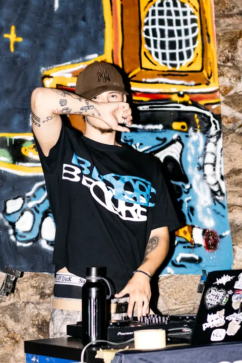 DJ za pultom pred veľkou maľovanou kulisou