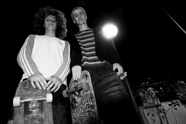 Dvaja skejteri so skateboardmi pod pouličnou lampou